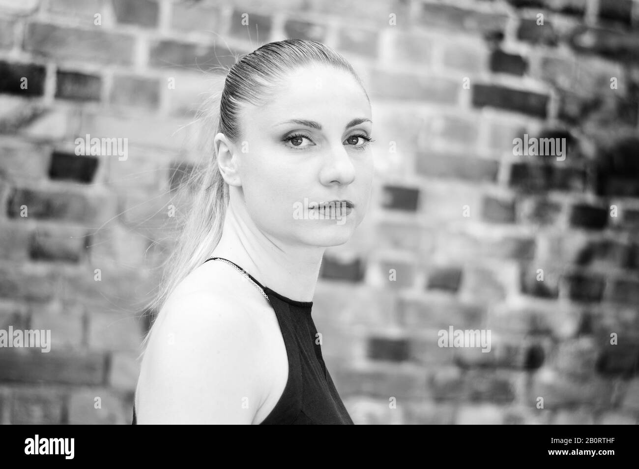 Donna millenaria in bianco e nero ritratto su muro di mattoni sfondo Foto Stock