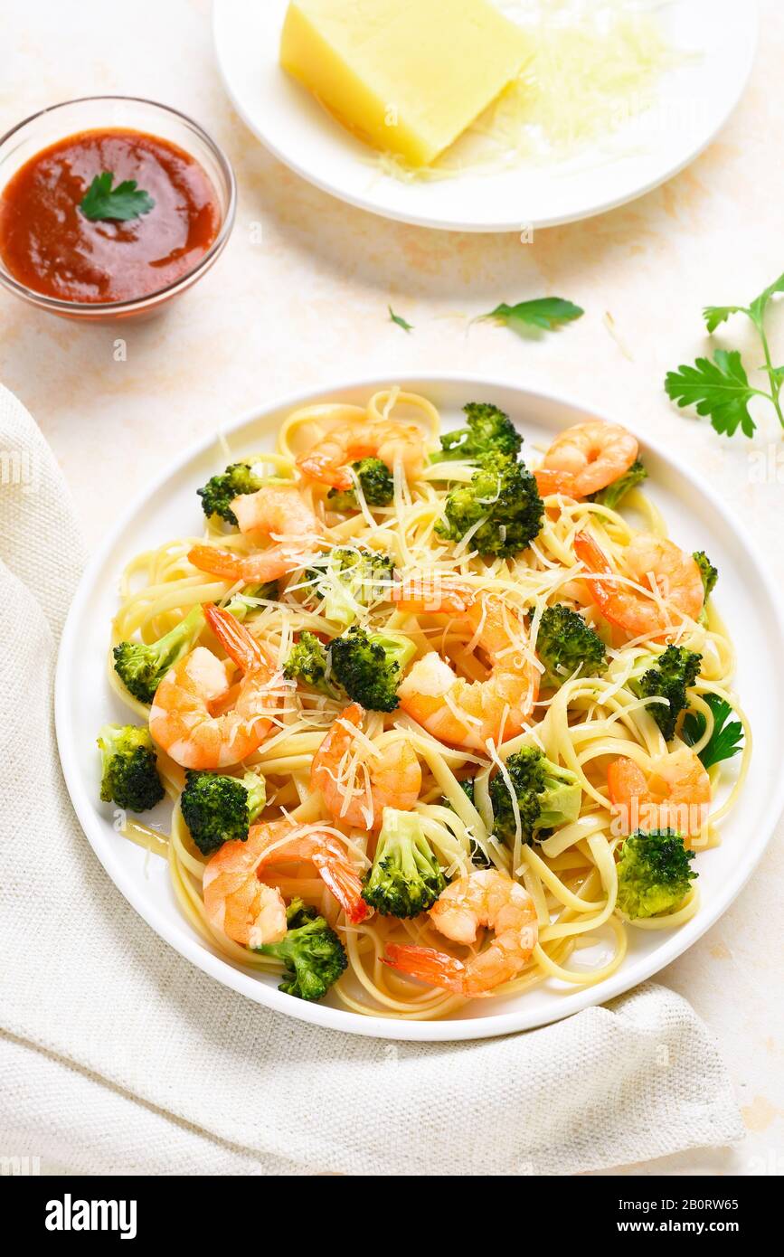 Pasta con gamberi, broccoli e parmigiano su piatto su un tavolo di pietra leggera. Gustoso piatto sano per cena. Foto Stock