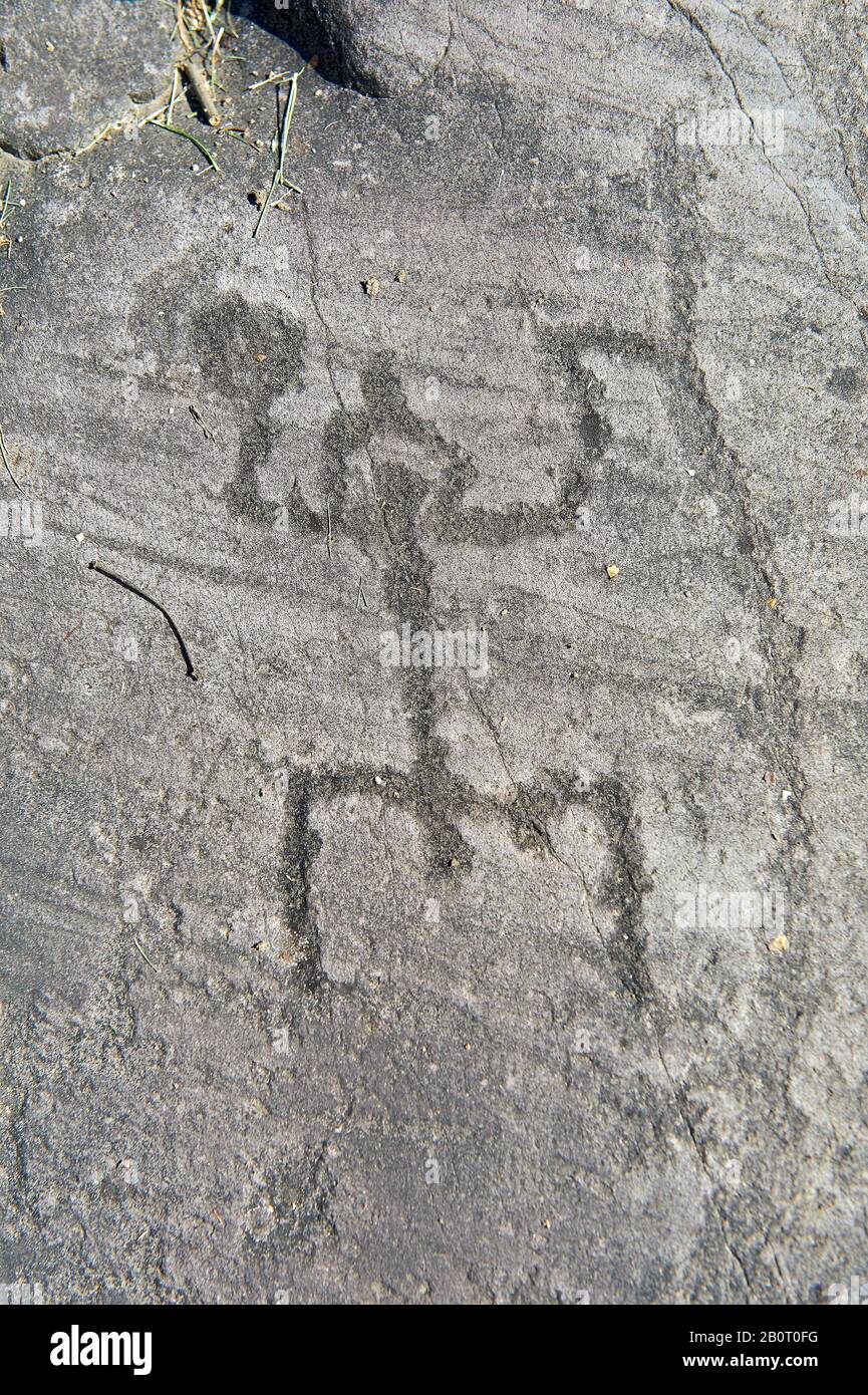 Petroglyph, scultura in roccia, di una figura umana schematica in posizione di "preghiera" indossando un casco smerigliato. Scolpito dagli antichi Camuni nel ferro Foto Stock
