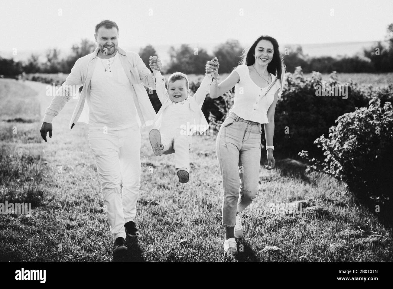 Buona famiglia che si posa su un campo verde. B&W. Foto Stock