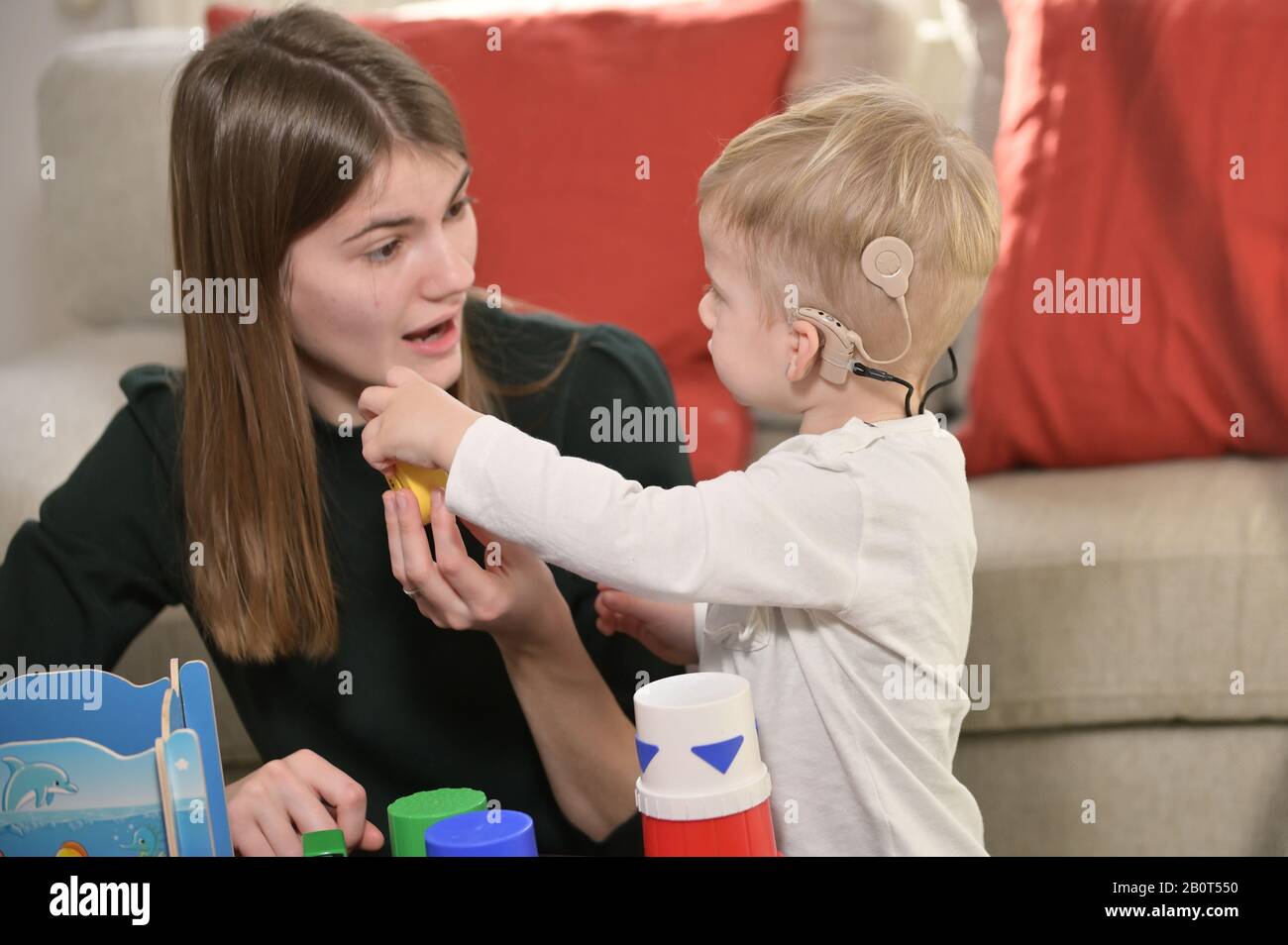 Un ragazzo Con impianti Cochlear giocando con sua madre Foto Stock