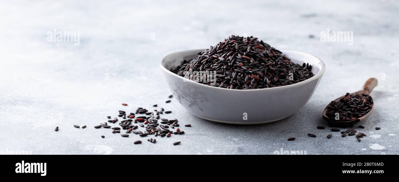 Riso nero selvatico in una ciotola. Sfondo grigio pietra. Foto Stock