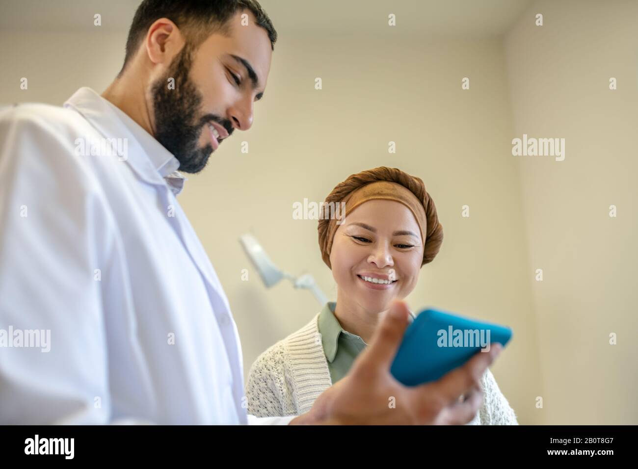 Bearded giovane medico e il suo paziente che parla Foto Stock