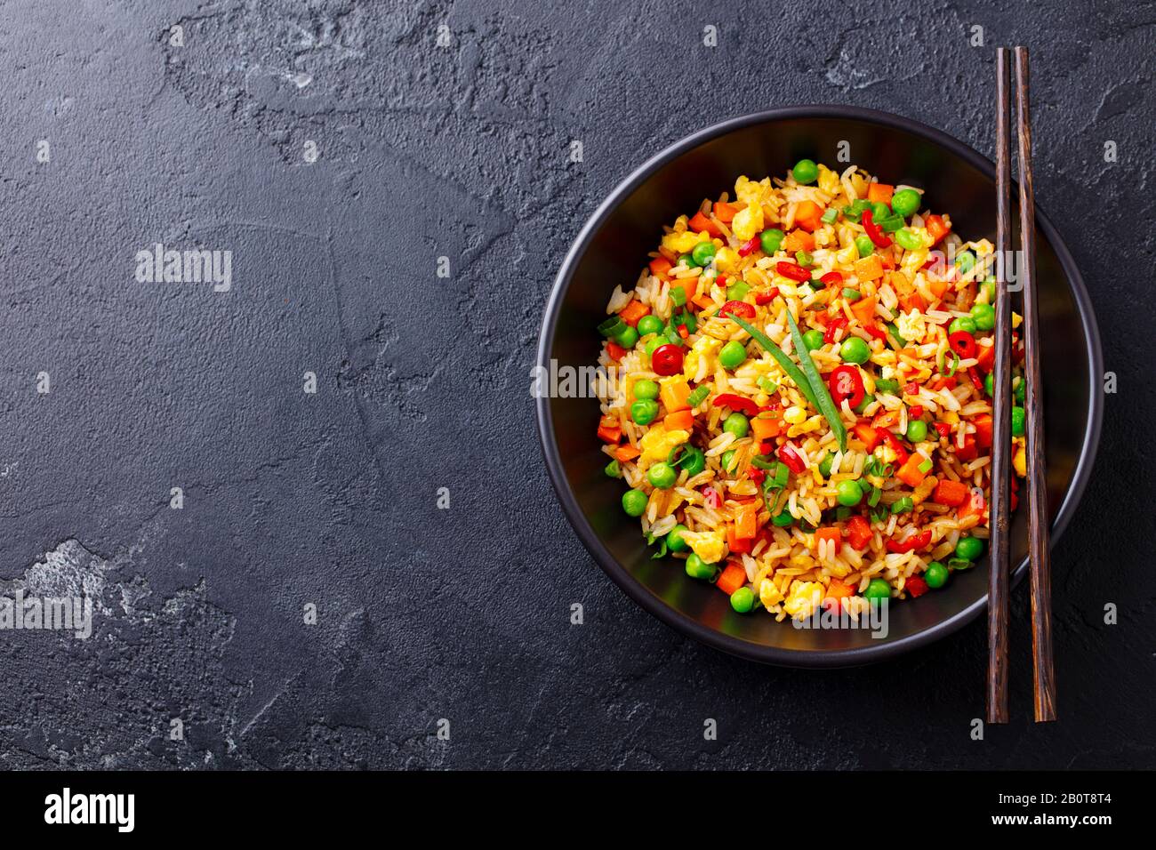 Riso fritto asiatico con uova e verdure. Sfondo nero. Spazio cimasa. Vista dall'alto. Foto Stock