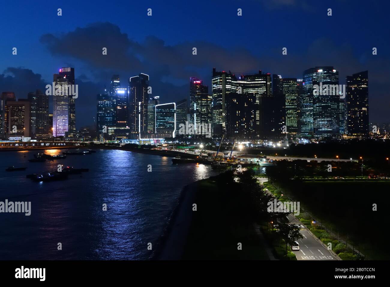 Lo skyline della città di Singapore inizia a illuminarsi in luce sbiadita dopo il tramonto Foto Stock