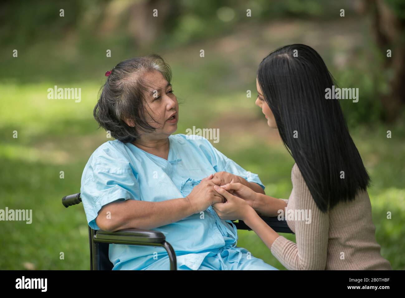 Nipote che parla con la nonna seduta su sedia a rotelle, concetto allegro, famiglia felice Foto Stock
