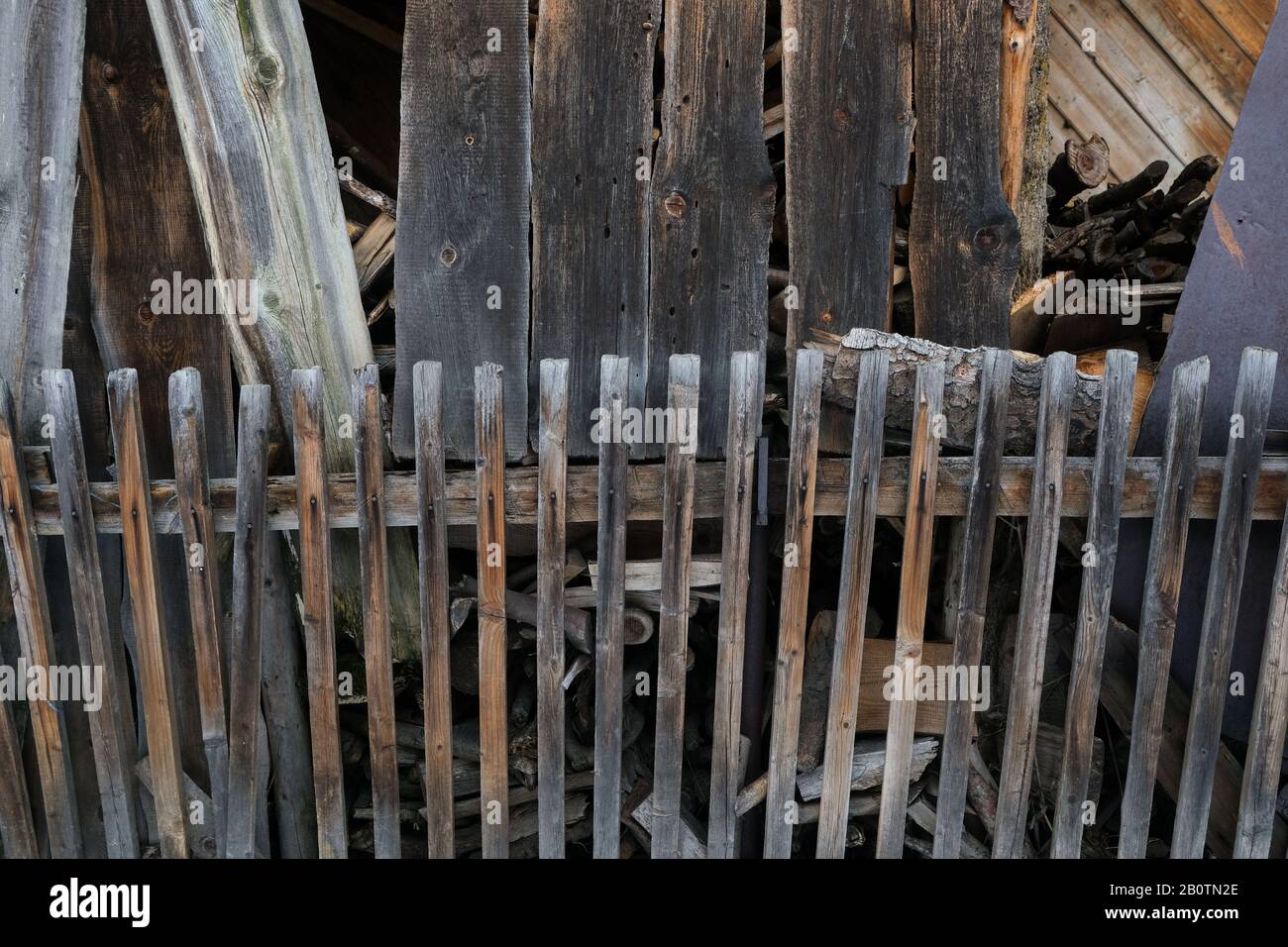 Polonia, Zakopane, Chochosow- 16 febbraio 2020: Vecchia recinzione in legno sullo sfondo di un vecchio edificio in legno, storiche capanne in legno a Chochosow Foto Stock