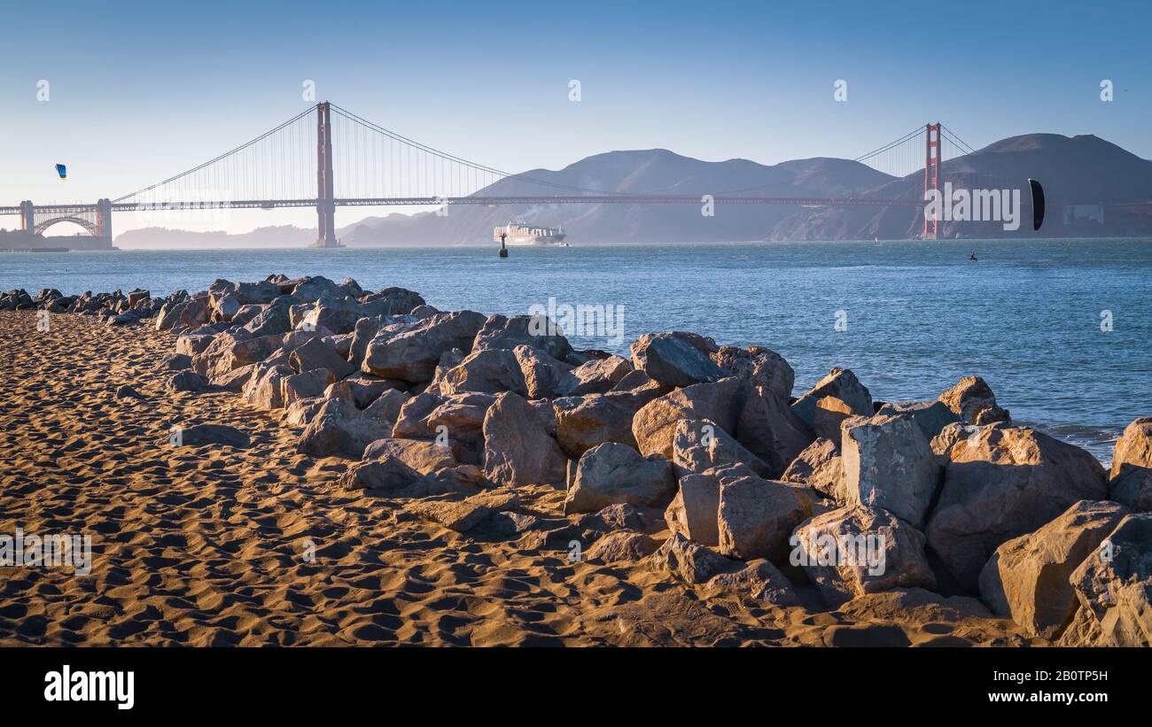 Kiteboarding la Baia di San Francisco. In lontananza, un'impressionante barca di carico che arriva da un luogo esotico e lontano si avvicina al Golden Gate Bridge. Foto Stock