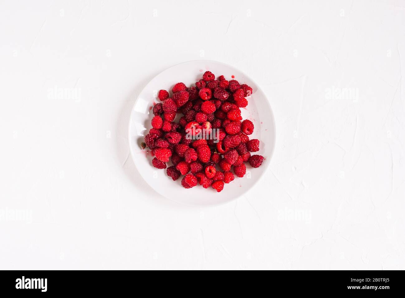 Piatto bianco con lamponi. Lamponi freschi isolati su sfondo bianco Foto Stock