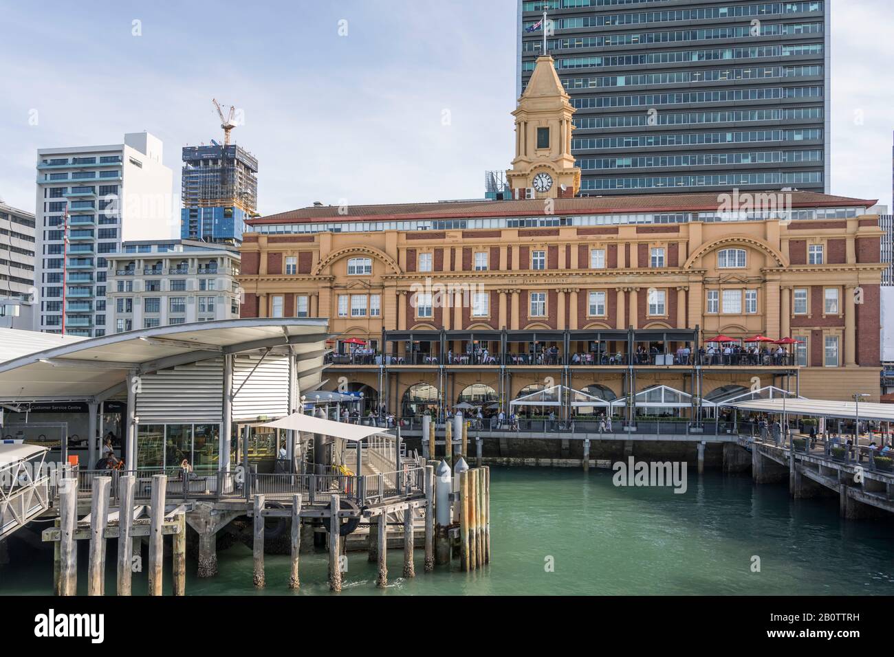 Auckland, NUOVA ZELANDA - 05 novembre 2019: Paesaggio urbano con banchine e storico edificio dei traghetti nel porto del dinamico centro della città, girato in ritardo luminoso Foto Stock