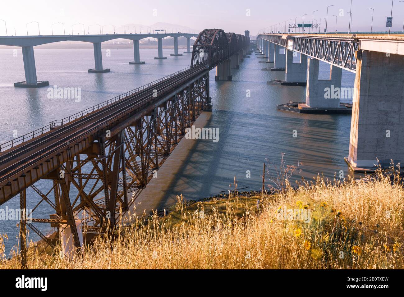 Benicia California, un vecchio ponte ferroviario arrugginito al primo semaforo. Ruggine, calcestruzzo e acciaio una grande giustapposizione di nuovo vs vecchio. Foto Stock