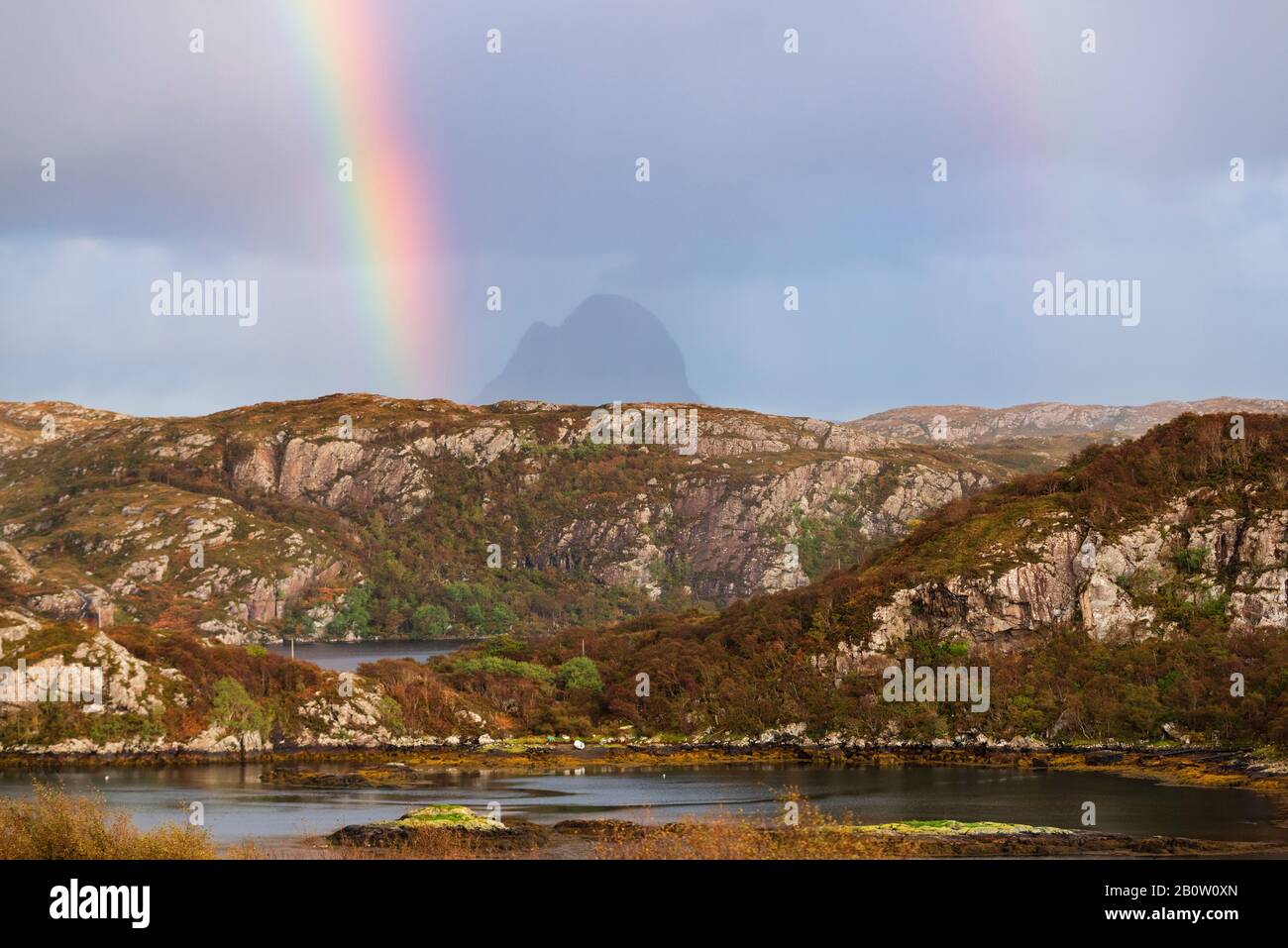 Arcobaleno nel cielo scuro sopra la montagna di Suilven in remoto paesaggio delle Highlands Scozzesi ad Assynt Nord Ovest della Scozia Foto Stock