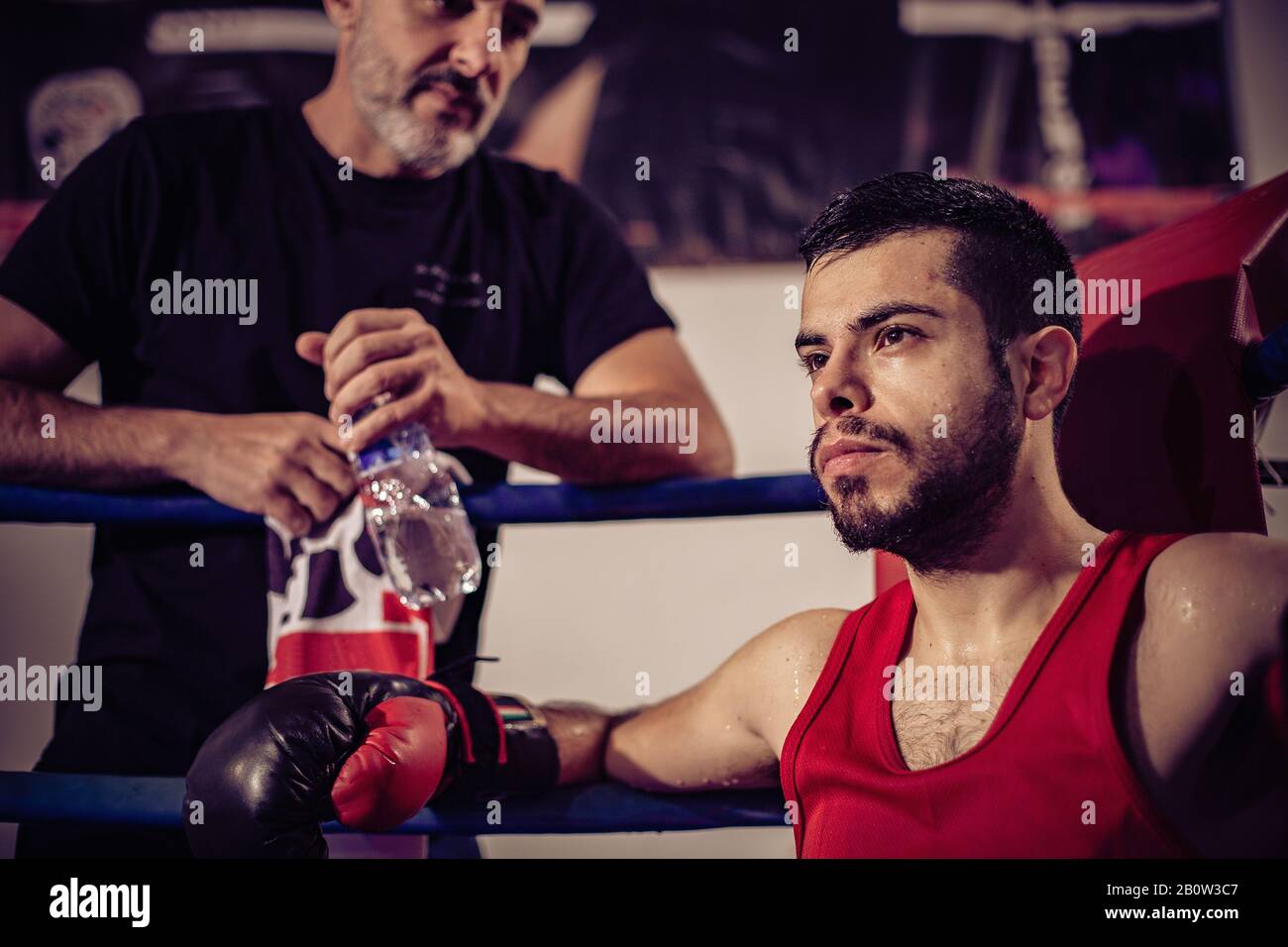 Ritratto di coach boxing e boxer maschio seduto in anello boxing. Foto Stock