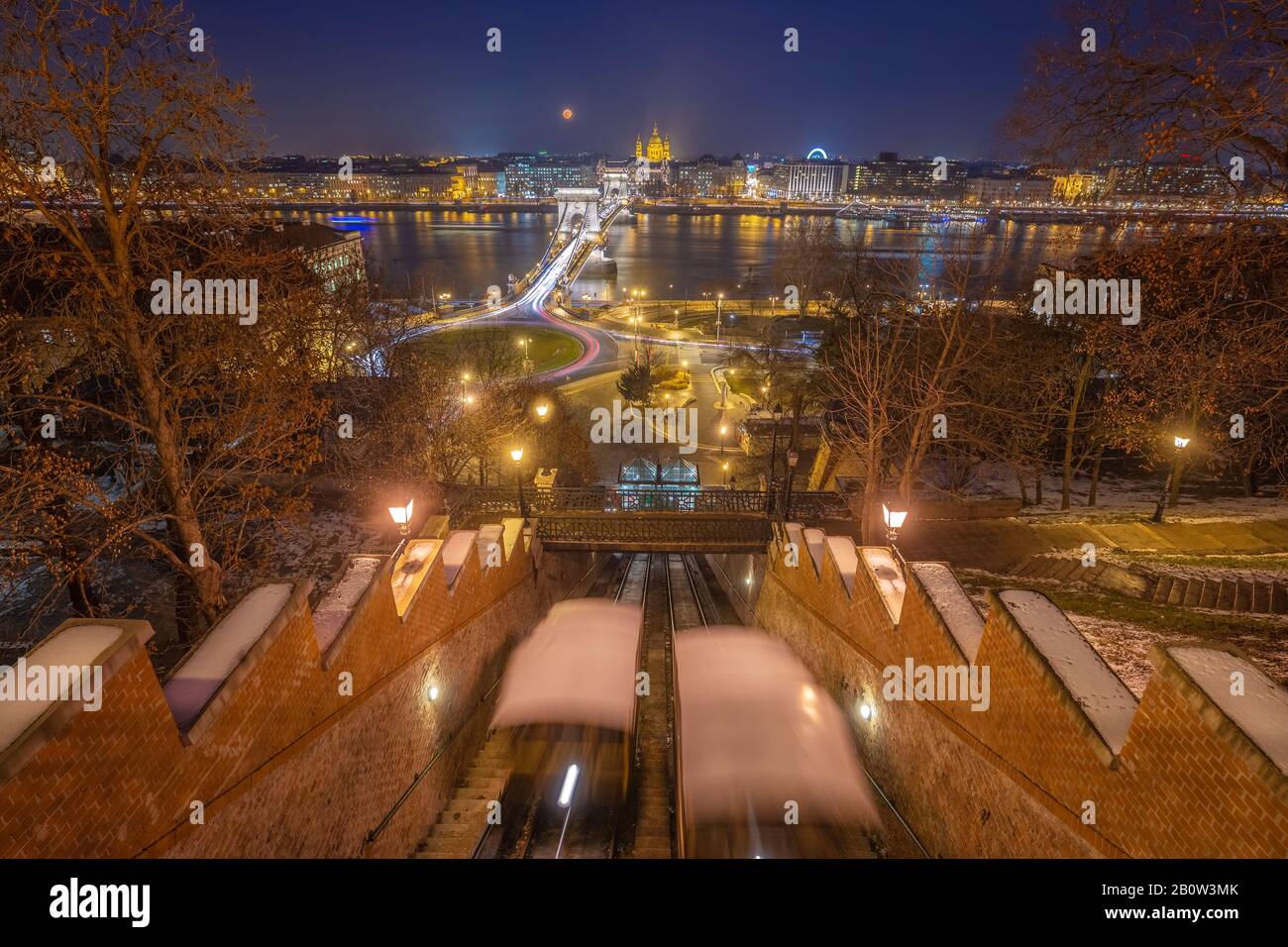 Budapest, Ungheria - Vista dalla collina del Castello di Buda a un'ora blu con funicolari mobili, il Ponte delle catene Szechenyi, la Basilica di Santo Stefano e la Luna sanguina Foto Stock