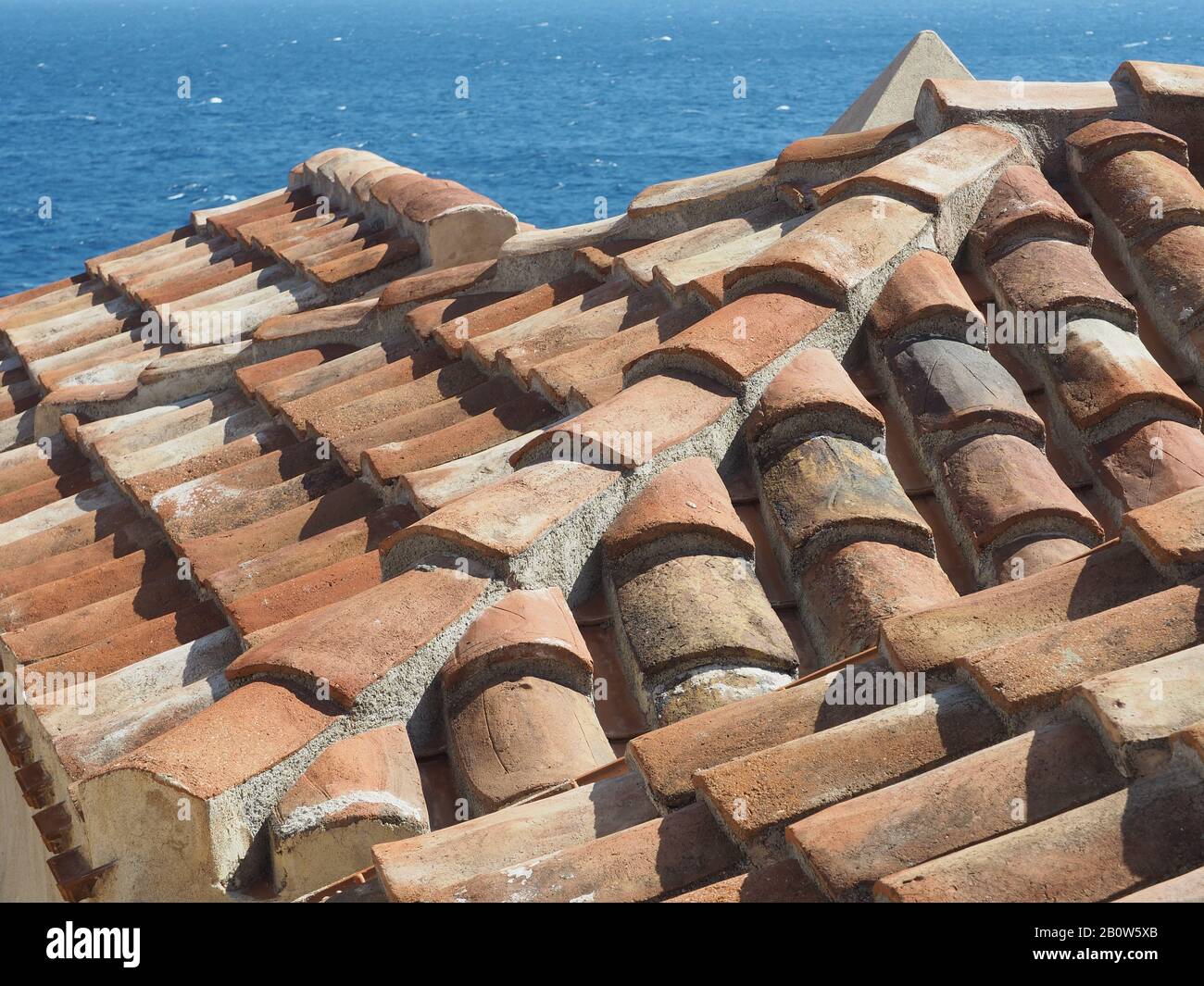 Particolare di tetti di tegole nelle mura, isola città di Monemvasia, Laconia, Peloponneso, Grecia. Mare blu sullo sfondo. Foto Stock