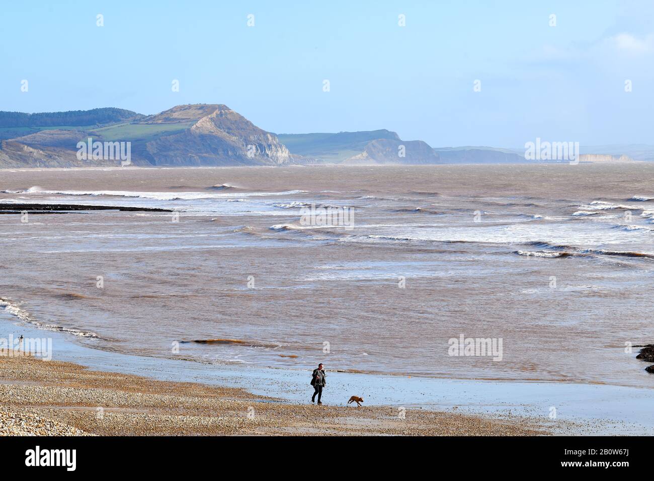 Onde dalla pausa canale Inglese sulla spiaggia di ghiaia di Lyme Bay, Lyme Regis, Dorset, Inghilterra con le scogliere della costa del Patrimonio (Jurassic), A. Foto Stock