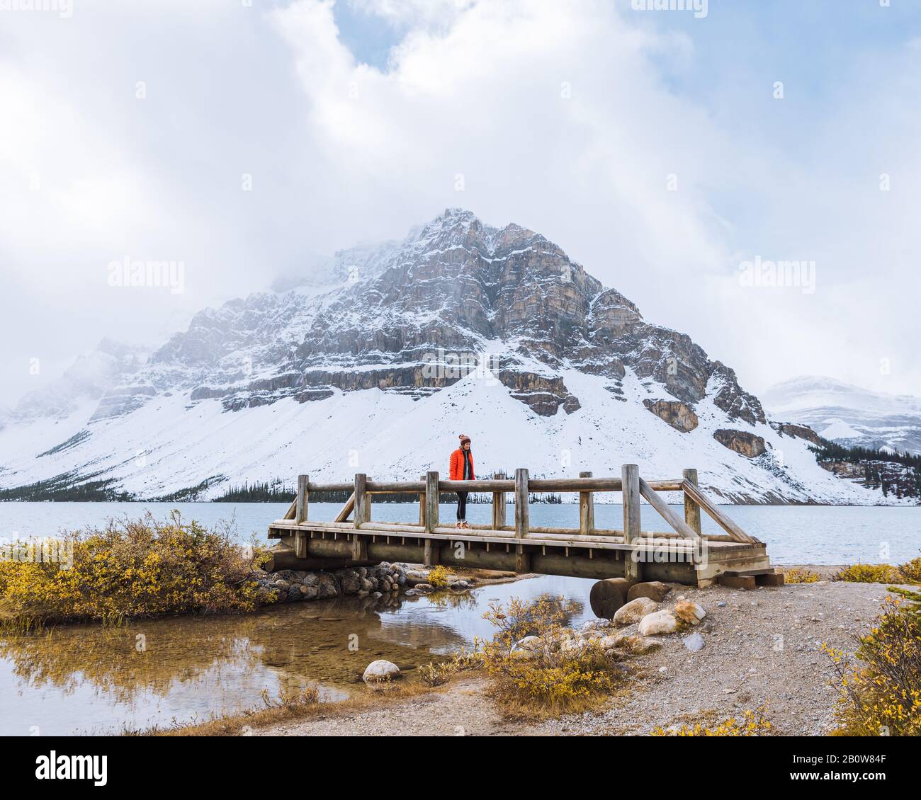 Hiker attraversando il ponte sul torrente in autunno, Bow Lake, Canadian Rockies, Alberta, Canada Foto Stock