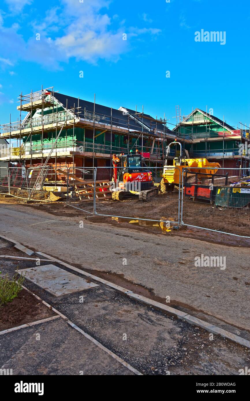 Nuovo sito di costruzione case con struttura in legno alla periferia di Bridgend. Recinzione di sicurezza intorno a luogo e pianta & attrezzatura. Foto Stock