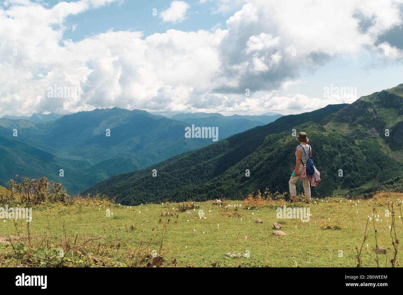 Donna in un prato di montagna con fiori bianchi Foto Stock