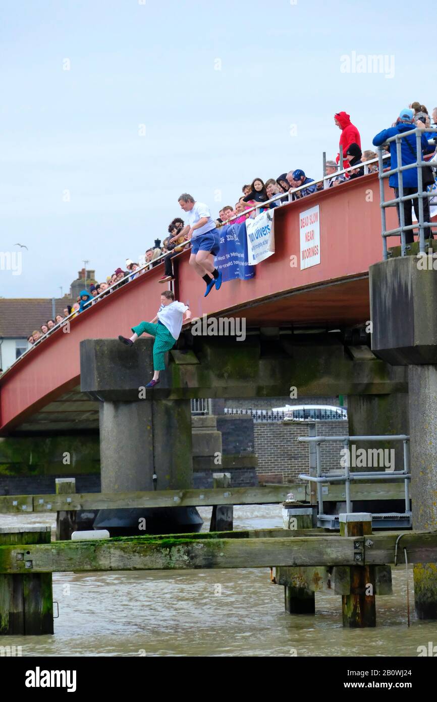 Le persone che saltano fuori da un ponte sul fiume Arun a Littlehampton, West Sussex in inverno per raccogliere soldi per la carità. Foto Stock