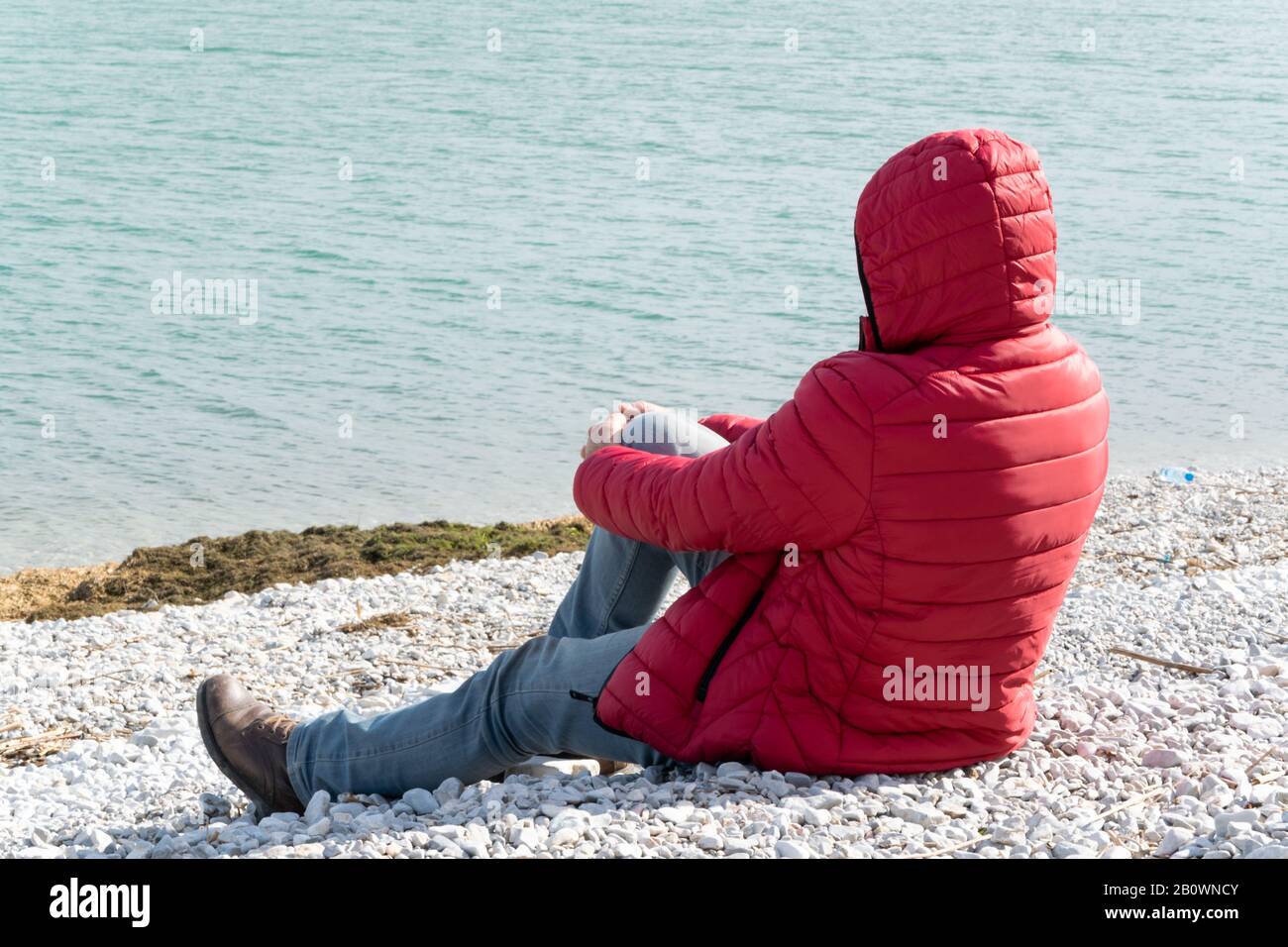Uomo solitario seduto sul lungolago, ammirando la natura. Persona irriconoscibile, wanderlust Foto Stock