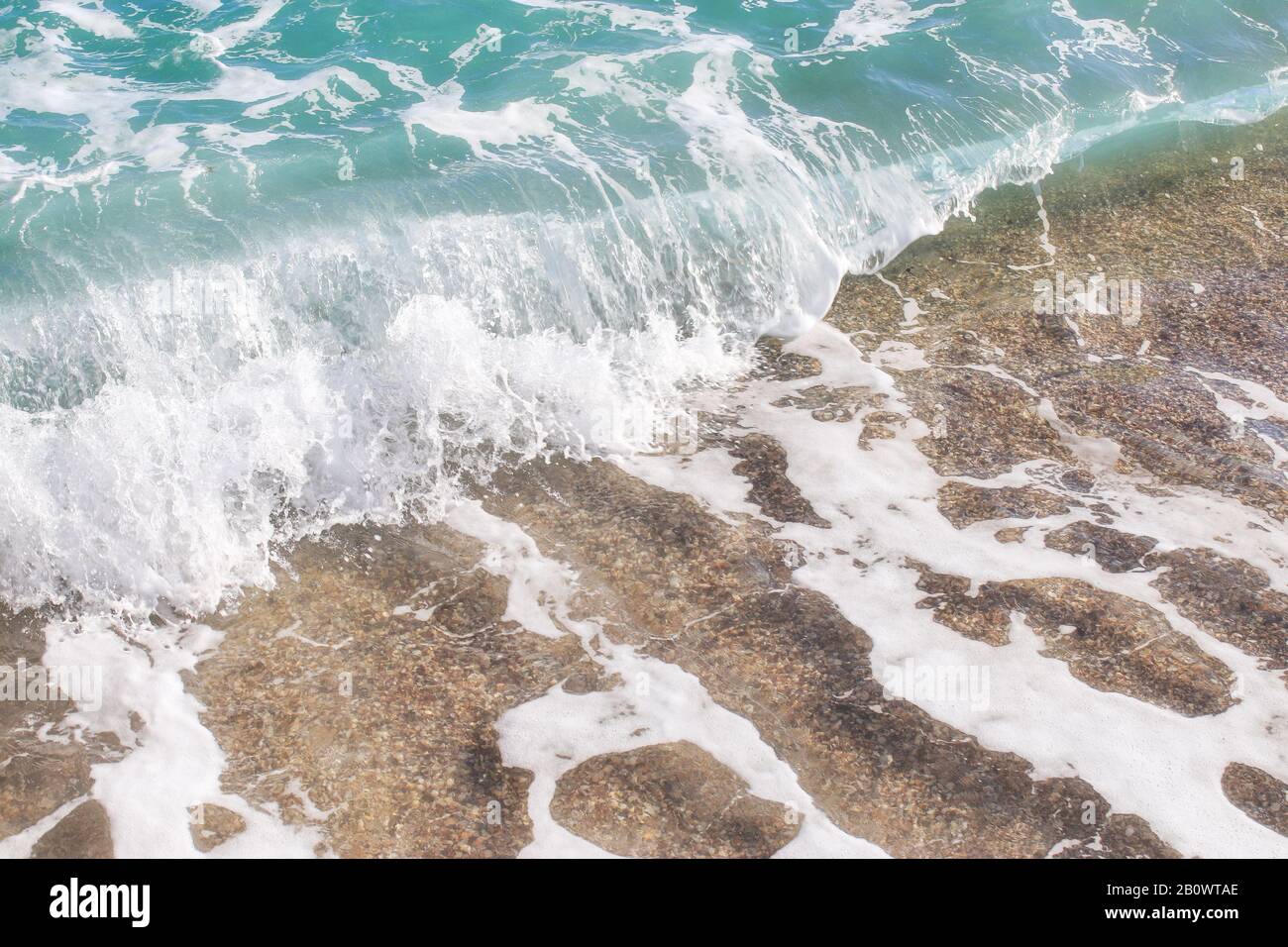 Struttura della spiaggia. Sabbia dorata e schiuma di mare. Sfondo spiaggia con spazio copia. Sfondo mare astratto. Vicino alle onde dell'oceano. Foto Stock