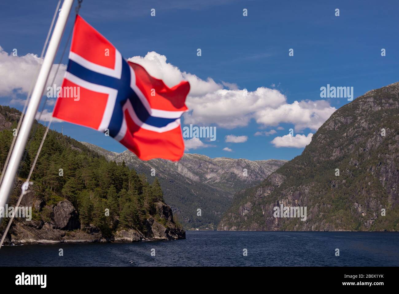 MOFJORDEN, NORVEGIA - bandiera norvegese su traghetto, navigazione e montagne nel fiordo. Foto Stock