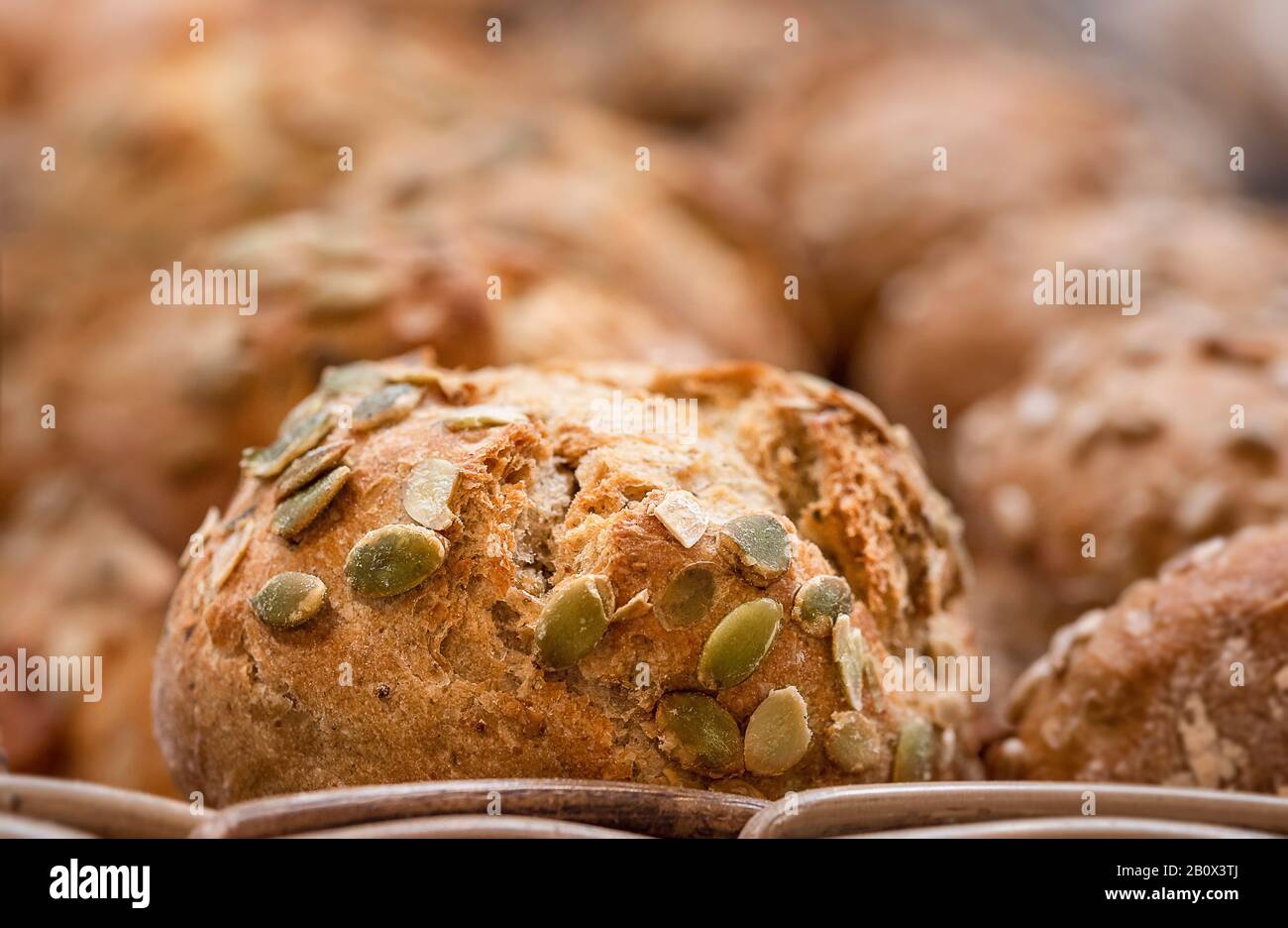 Sourdough pane bun con semi da vicino. Mucchio di mini pani sani organici. Pane appena sfornato. Sfondo di semi di zucca pane Foto Stock