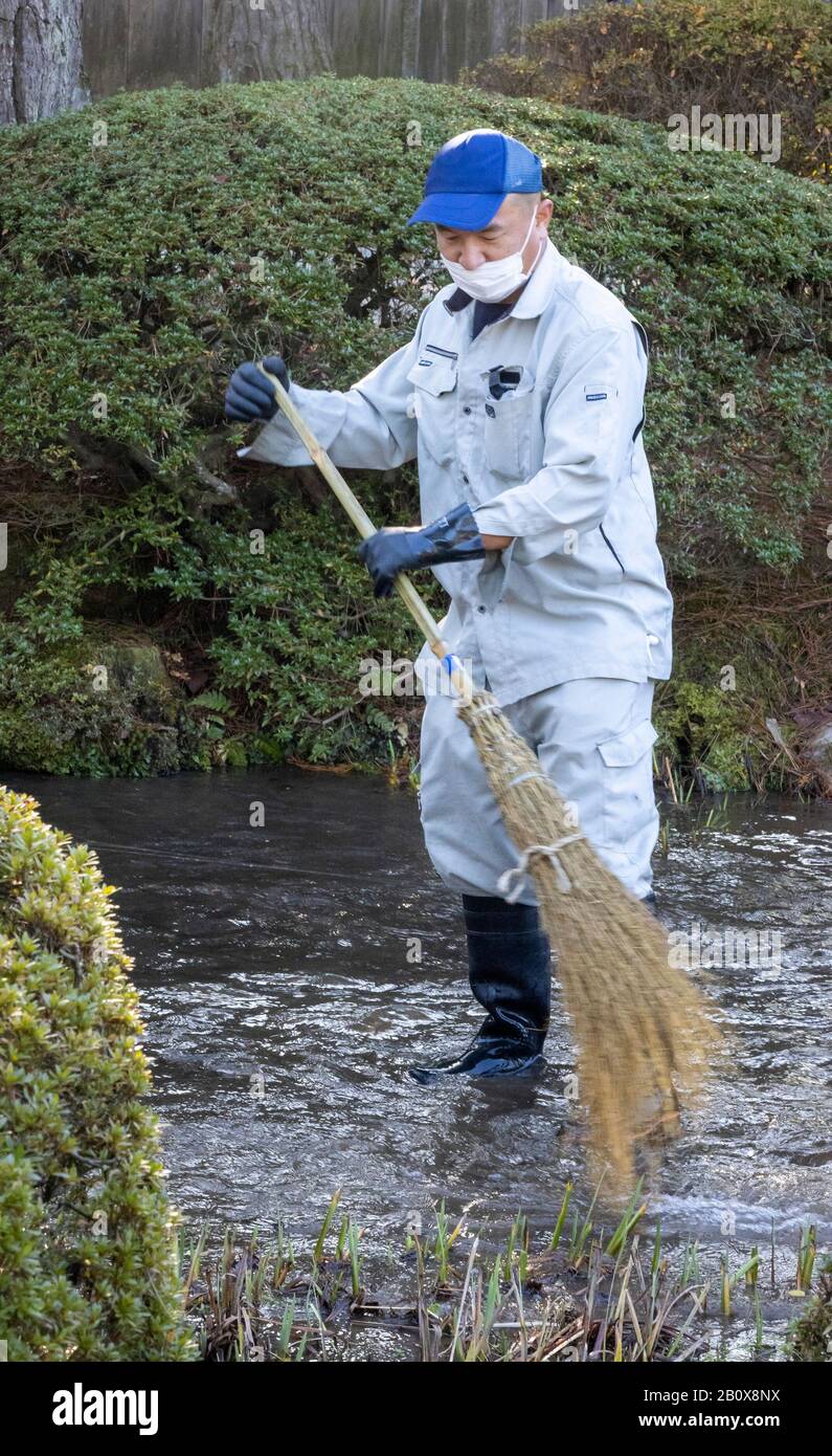 Lavoratore pulizia fiume con spazzola, Kenroku-en Garden, Kanazawa, Giappone Foto Stock