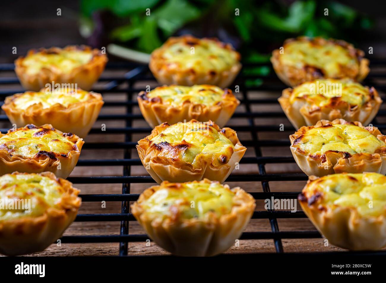 Tazze di pasta filata riempite con miscela feta su una griglia di raffreddamento nera. Foto Stock
