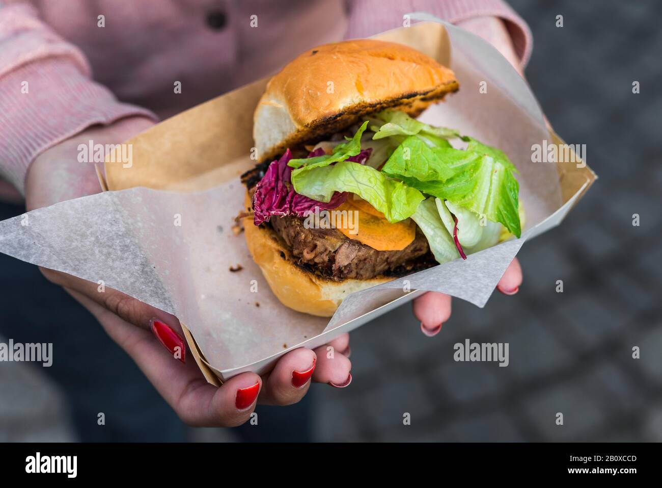 Giovane donna che mangia un hamburger di carne di anatra in un mercato alimentare di strada. Foto Stock
