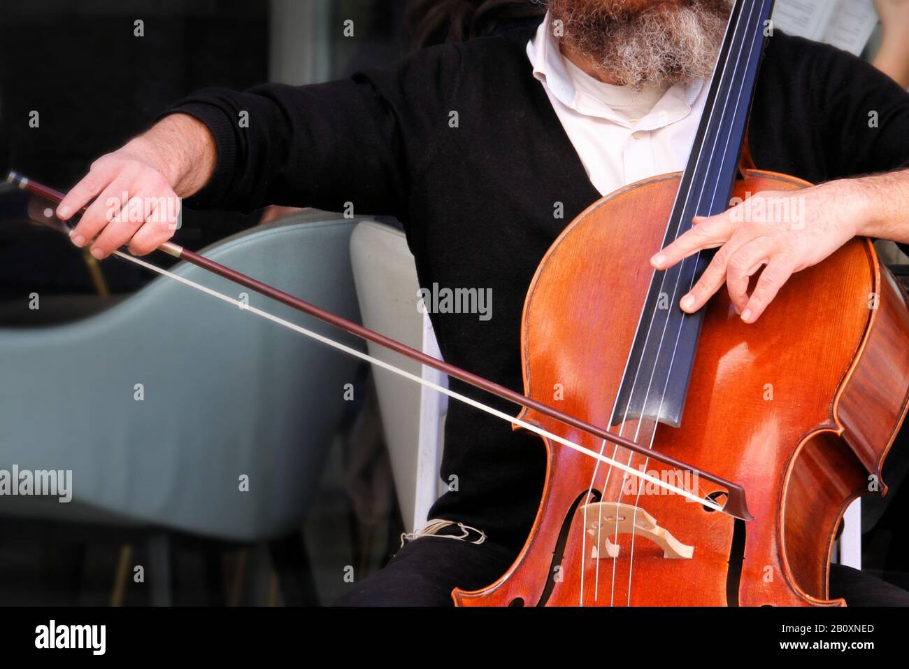 Una vista ravvicinata delle mani di un esecutore di strada mentre suona il violoncello. Foto Stock