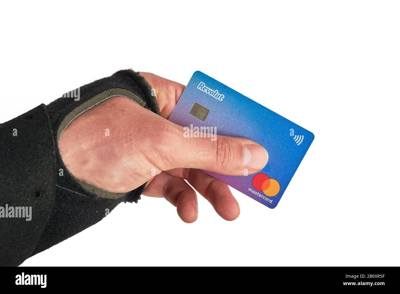 Bucarest, Romania - 13 aprile 2019: Revolut Master Card tra le dita di una mano che indossa un braccialetto da polso, dopo una ferita da sci. Foto Stock