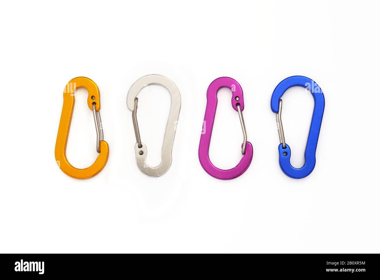 Quattro moschettoni con porta a filo piccolo non utilizzati per l'arrampicata, ma per appendere accessori o chiavi. Moschettoni colorati isolati su sfondo bianco - TOP dow Foto Stock