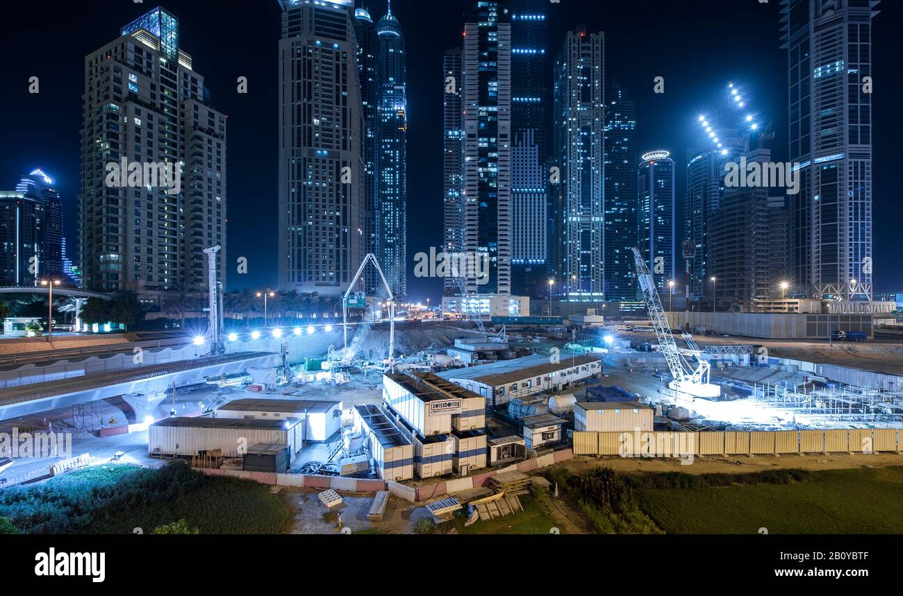 Cantieri edili, illuminazione e edifici di alto livello di notte a Marina, New Dubai, Emirati Arabi Uniti, Foto Stock