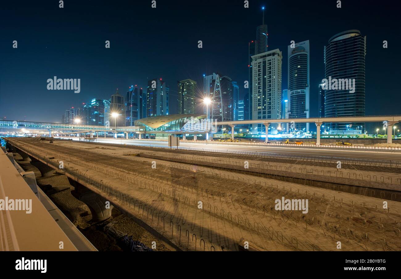 Vista del sito di costruzione del Tram System al Soufouh a Marina con grattacieli delle Jumeirah Lakes Towers (JLT) di notte, New Dubai, Emirati Arabi Uniti, Foto Stock