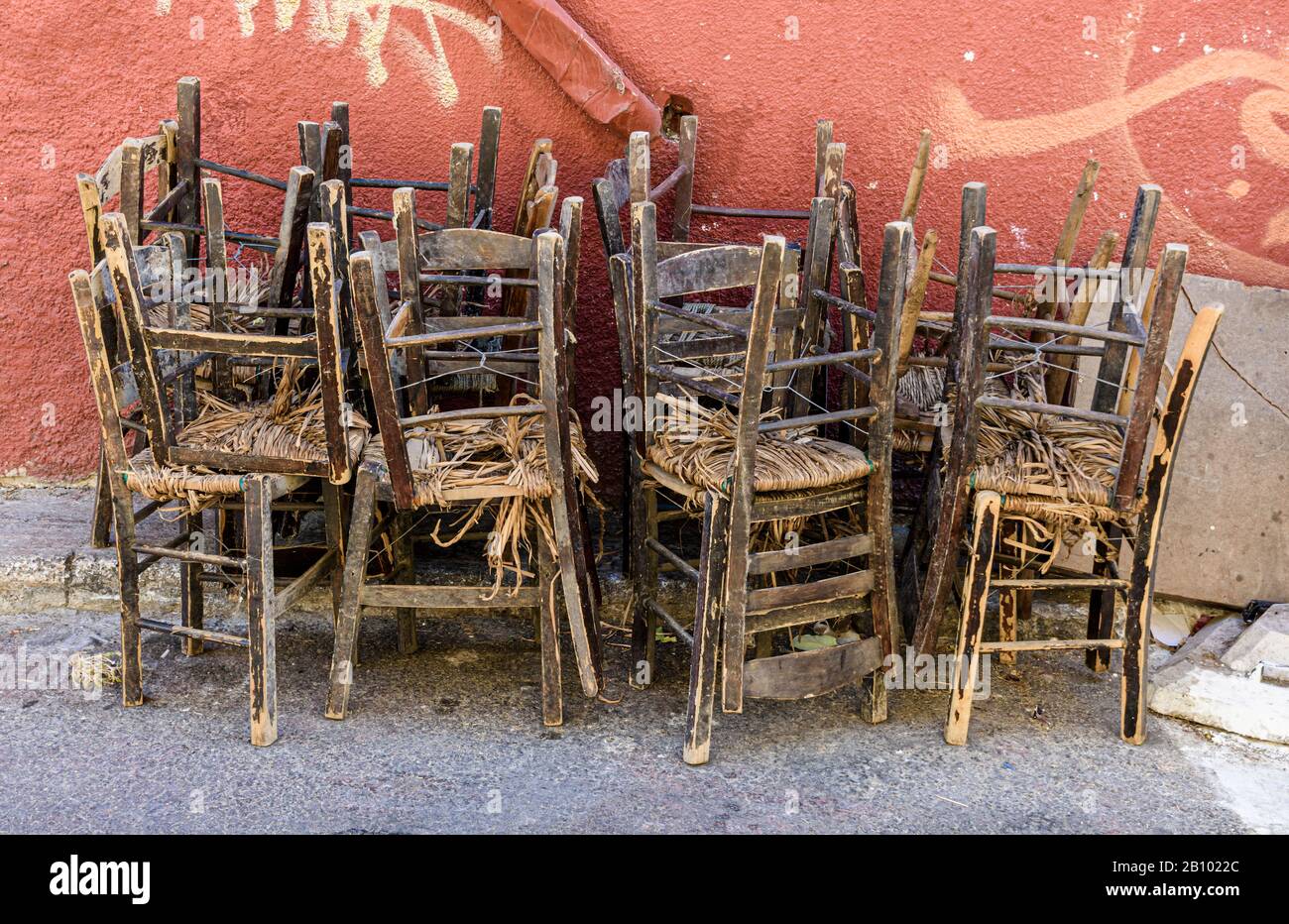 Vecchie sedie, accatastate contro una parete Foto Stock
