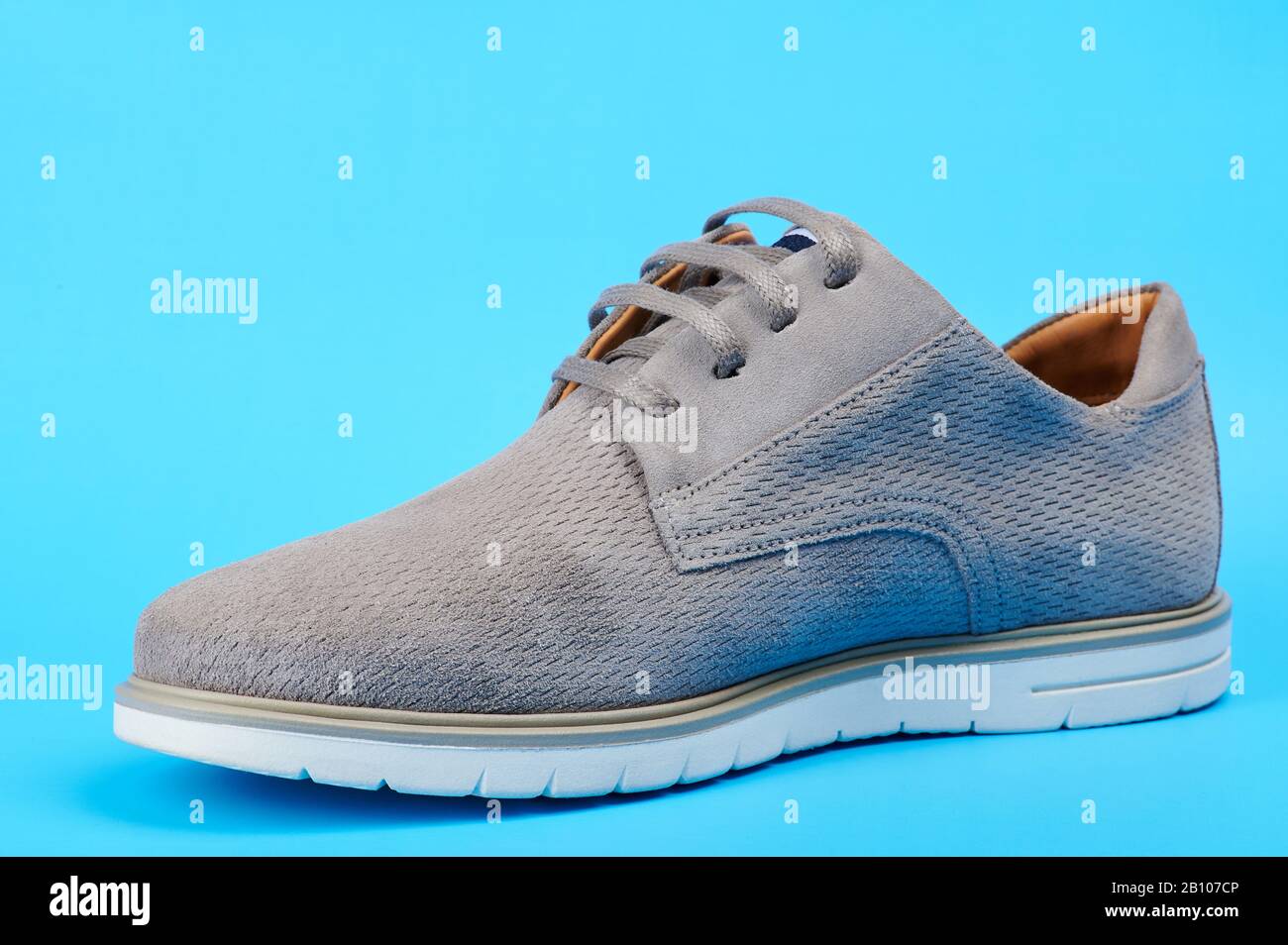 Una scarpa casual grigia uomo isolata su sfondo blu Foto Stock