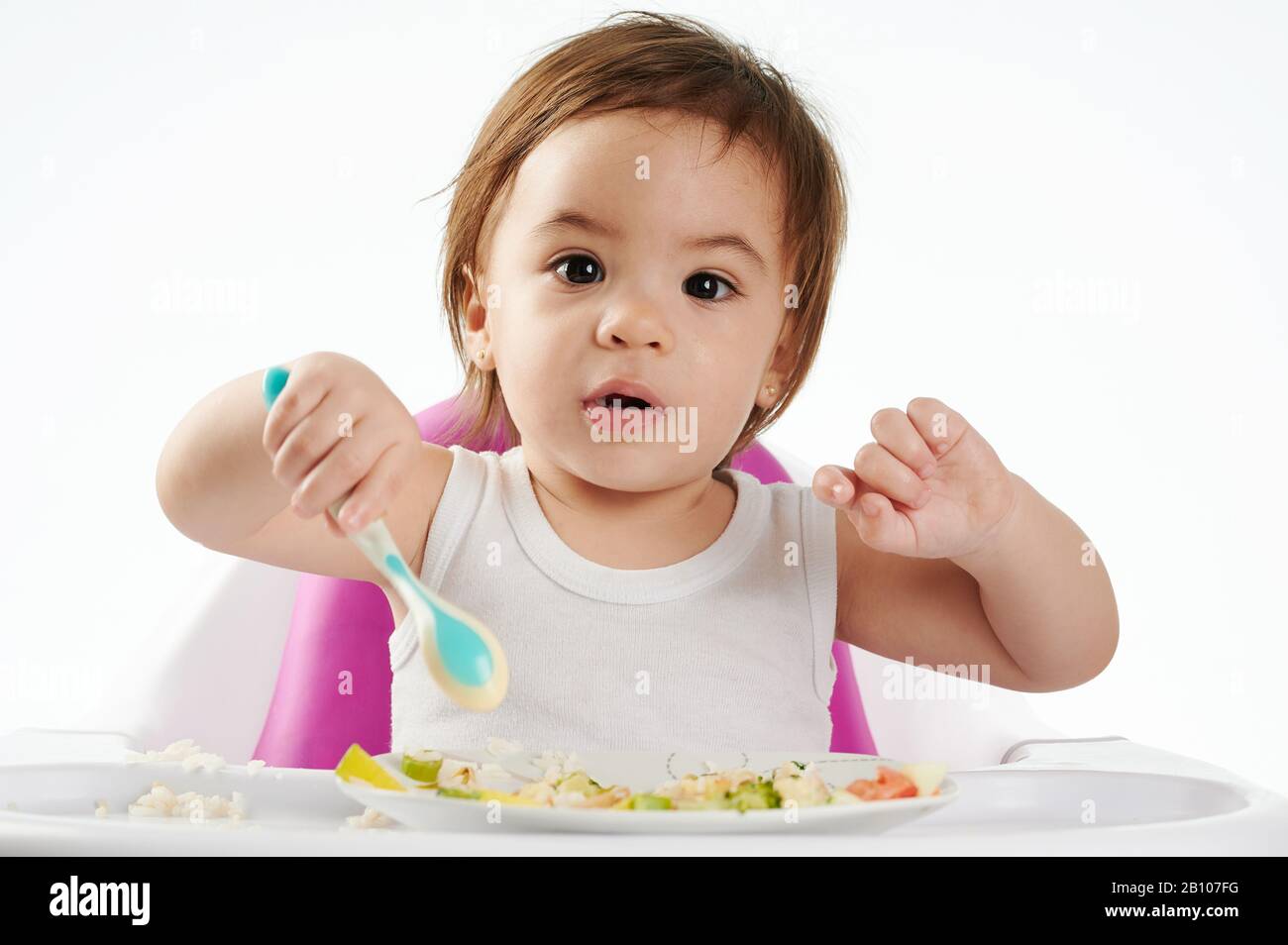 Cute baby mangiare cibo sano su sedia alta isolato Foto Stock