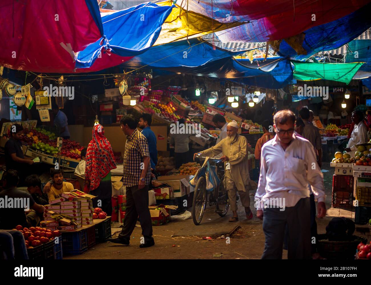 Mumbai, India - 18 dicembre 2019 : uomo musulmano di vecchia età che indossa i panni islamici tradizionali e la testa del cranio che cammina con la bicicletta in un mercato della frutta a Sout Foto Stock