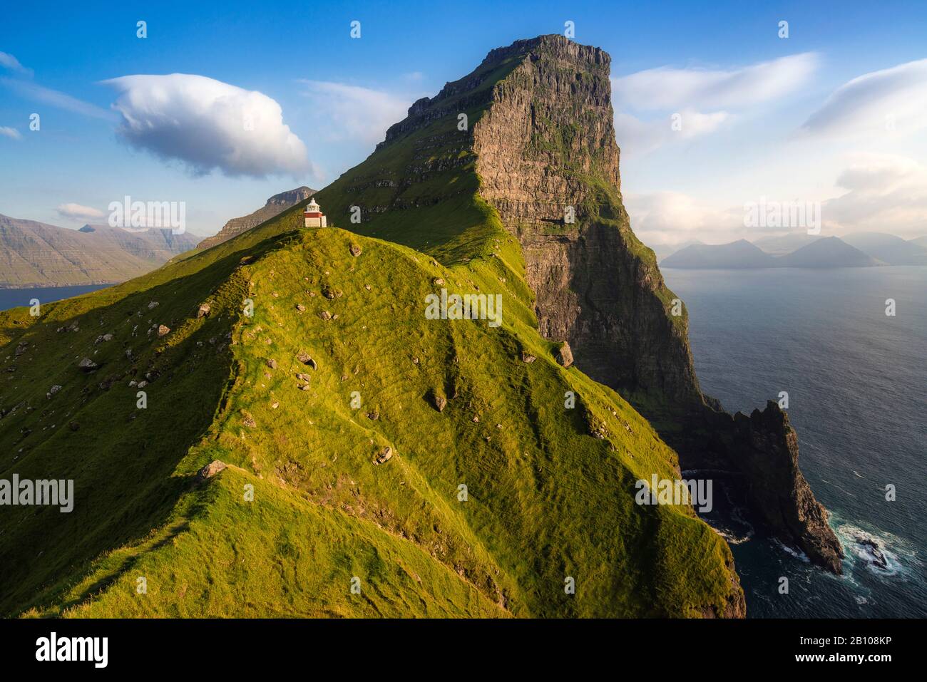 Faro sulla scogliera nella luce della sera, Kalluar, Kalsoy, Isole Faerøer, Danimarca Foto Stock