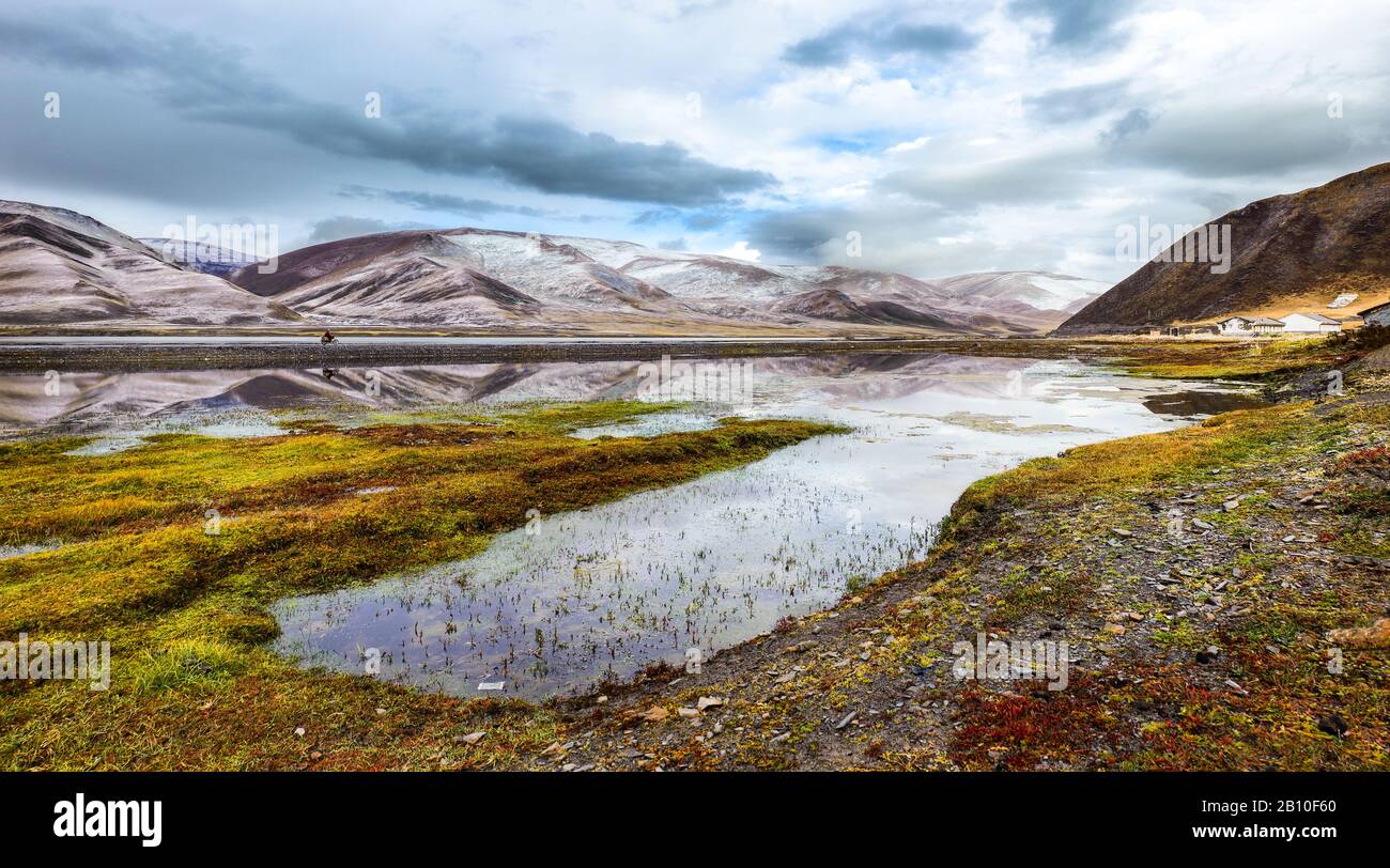I monaci buddisti si pedalano su una motocicletta sopra un bacino di acqua sull'altopiano tibetano, provincia del Sichuan, Cina Foto Stock