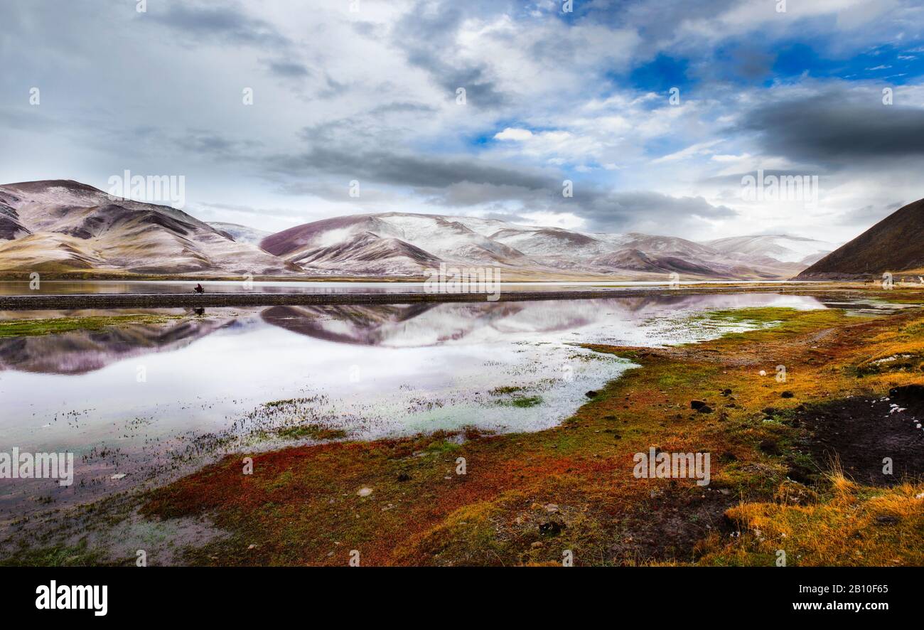 I monaci buddisti si pedalano su una motocicletta sopra un bacino di acqua sull'altopiano tibetano, provincia del Sichuan, Cina Foto Stock