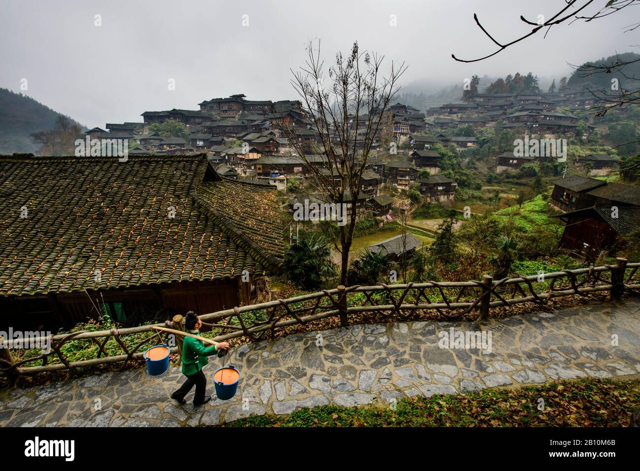 Miao donna porta rifiuti alimentari a XiJiang, villaggio tradizionale della minoranza etnica Miao. Provincia Di Guizhou, Cina Foto Stock