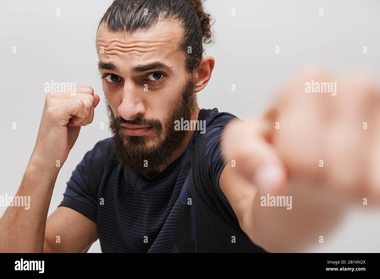 Immagine di giovane sportivo bruna che indossa la boxe con tuta a macchina fotografica isolata su sfondo bianco Foto Stock