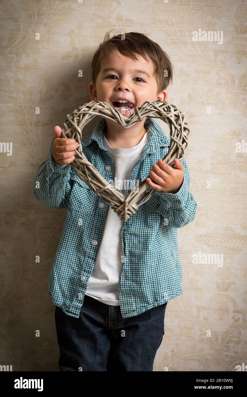 Ragazzino tiene in mano il cuore di legno Foto Stock