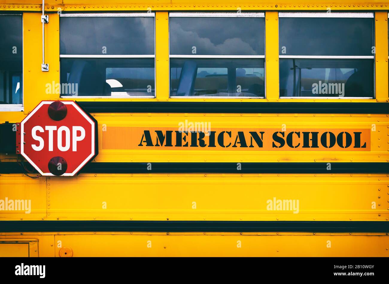 Classico autobus giallo americano che trasporta i bambini alla scuola. Torna al concetto di scuola. Segnale di fermata rosso sul lato dell'autobus della scuola. Foto Stock