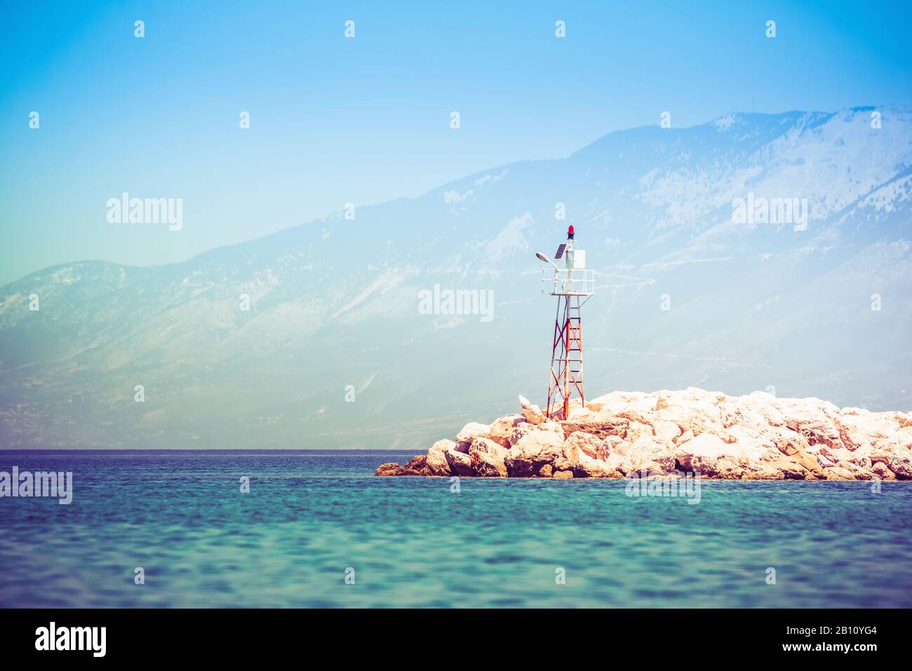 Faro di mare sulla riva rocciosa all'alba Foto Stock