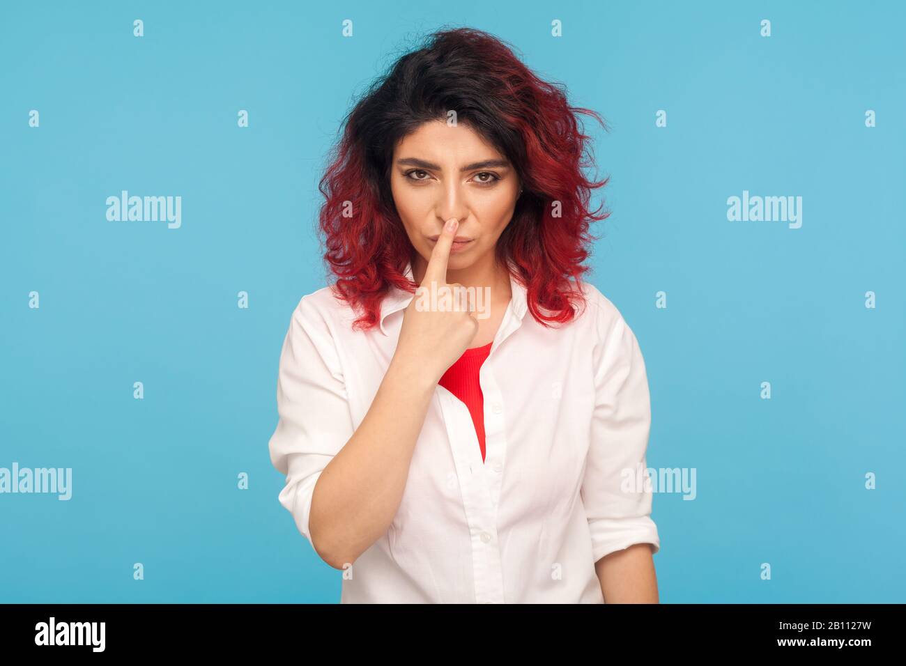 Segno di falsità. Ritratto di arrabbiato dispiaciuto donna con fantasia capelli rossi in camicia bianca che tocca il naso con il gesto di menzogna, incolpando per inganno, falsità. IND Foto Stock