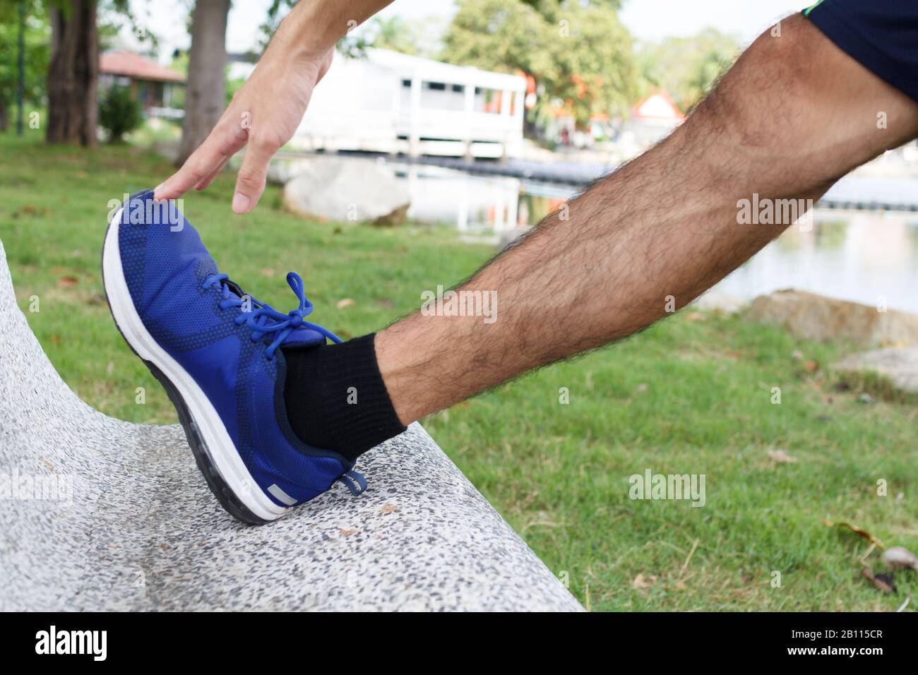 Sport giovane uomo runner stretching gambe prima di correre - concetto di allenamento Foto Stock